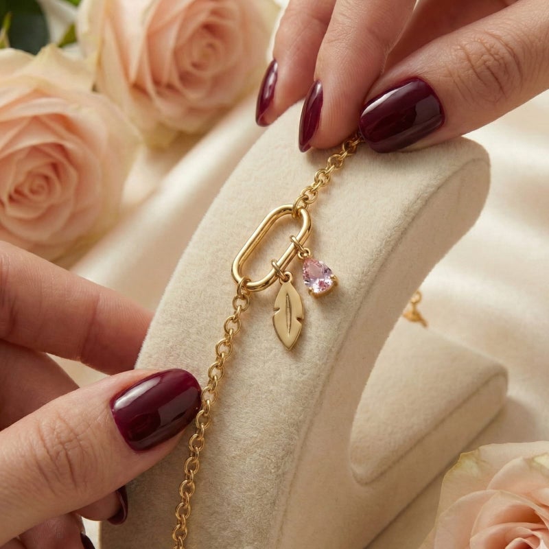 This attractive gold bracelet, crafted from rust-resistant stainless steel, features a modern link ring from which a delicate feather and a sparkling pink stone dangle. It has an adjustable clasp for a perfect fit. - Image 5